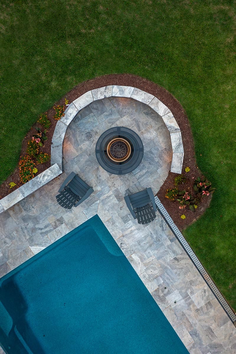 Aerial top view of modern pool and installation by Setting Sun Patio featuring fire pit and retaining wall.