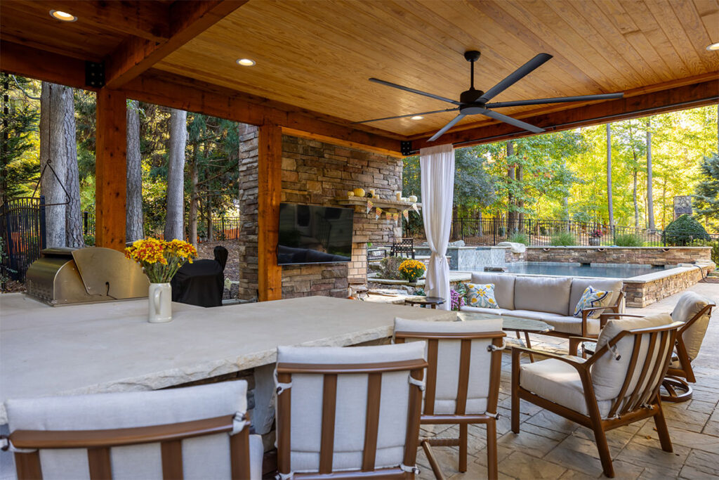 Corner view of Trenton Woods front outdoor kitchen facing directly at the fireplace with tv.