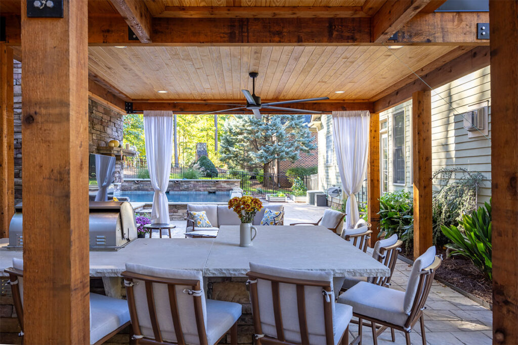 Interior shot underneath pavilion looking at outdoor kitchen and pool.