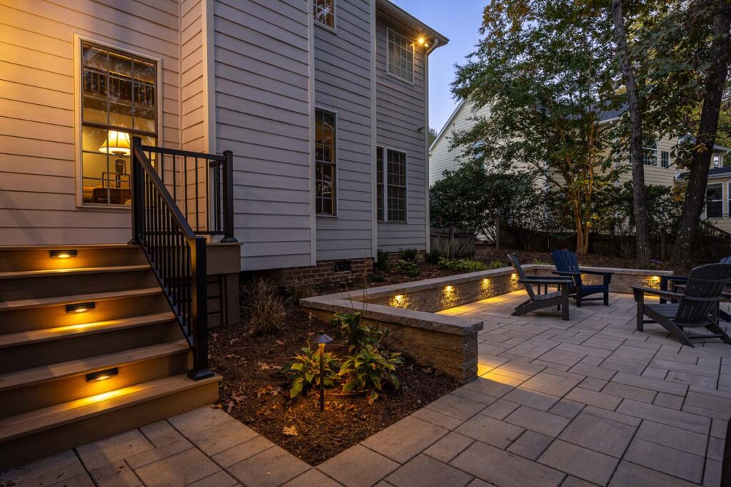 Night scene of Banyon Tree showcasing composite steps with low-voltage lighting and retaining wall surrounding patio.