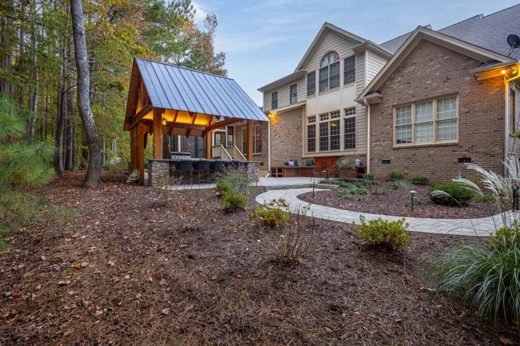 Ground view looking upwards showing pavilion and Colvard Park home with shrubs in the foreground.