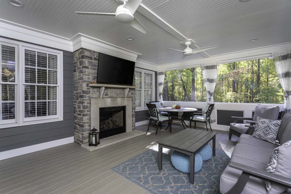 Wide view of interior deck, Northlake project, showing fireplace with television, a dining table, and coffee table.