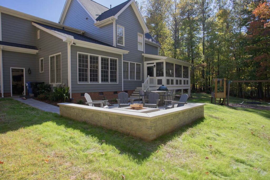 Patio area of North lake with Techo-Bloc pavers. Featuring fire pit and outdoor grill with countertop, showing entrance to screen deck and garage.