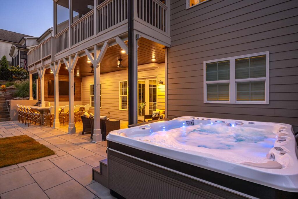 Three-quarter shot facing towards composite deck with jacuzzi in the foreground and outdoor kitchen in the background.