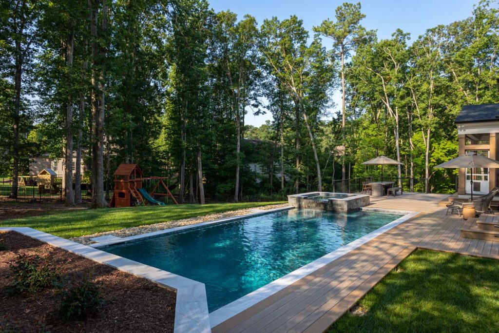 Royal Amber patio from wide shot, showcasing retaining wall in the foreground and pool waterfall in the background.