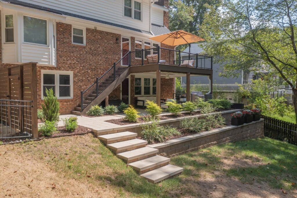 Wide shot of Rushing Brook patio, with composite deck, wooden entry door, steps and retaining wall.