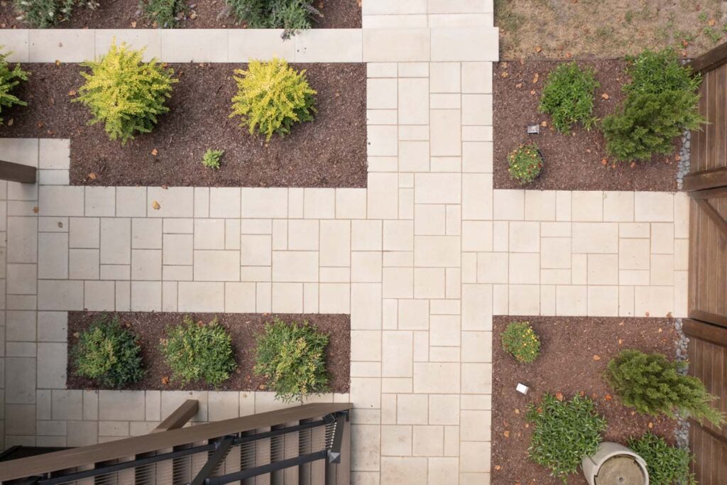 Top view of pathway of Rushing Brooks, connecting the inside patio to wooden entry door, patio steps, and lower backyard.