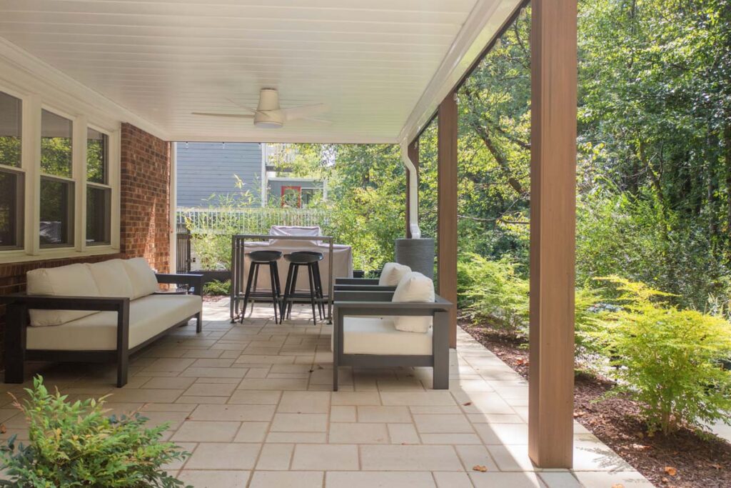 Close up of Rushing Brook deck, with two outdoor sofas and shrubs. Featuring patio door and stairs leading to the elevated deck.