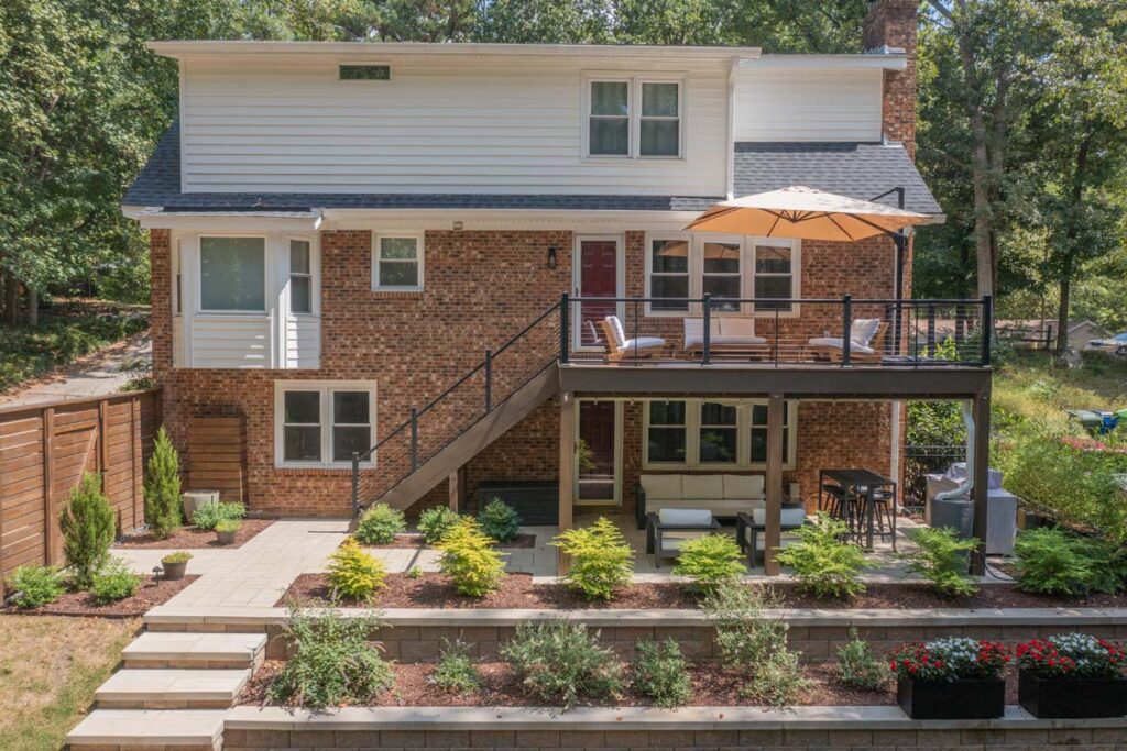 Wide shot of Rushing Brook patio, with composite deck, wooden entry door, steps and retaining wall.