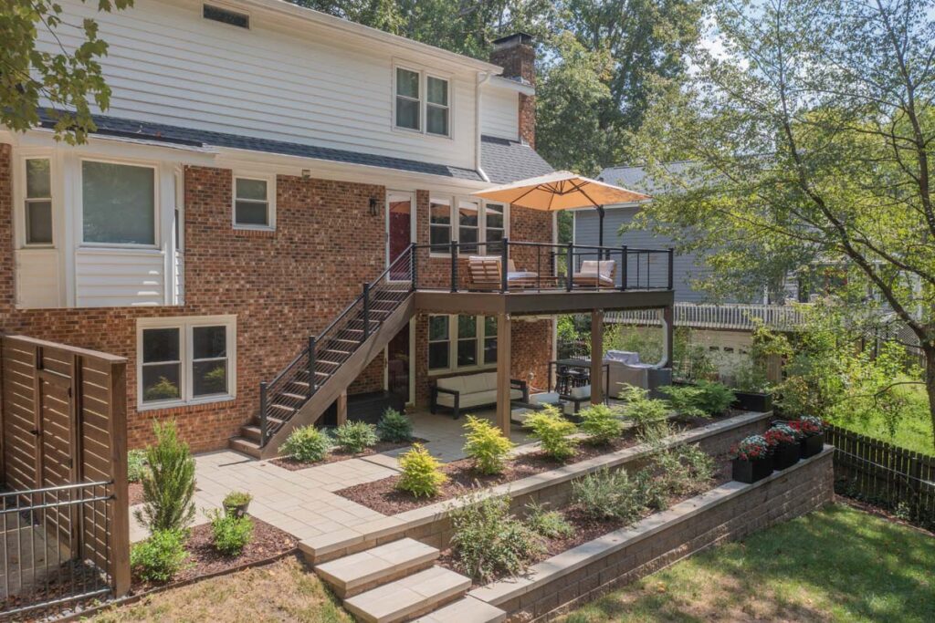 Wide shot of Rushing Brook patio, with composite deck, wooden entry door, steps and retaining wall.