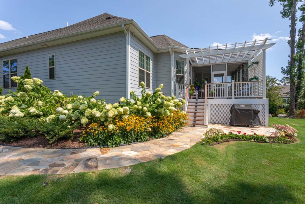 Wide shot of Silver Dew facing composite deck. Showcasing garden surrounding home and walk way.