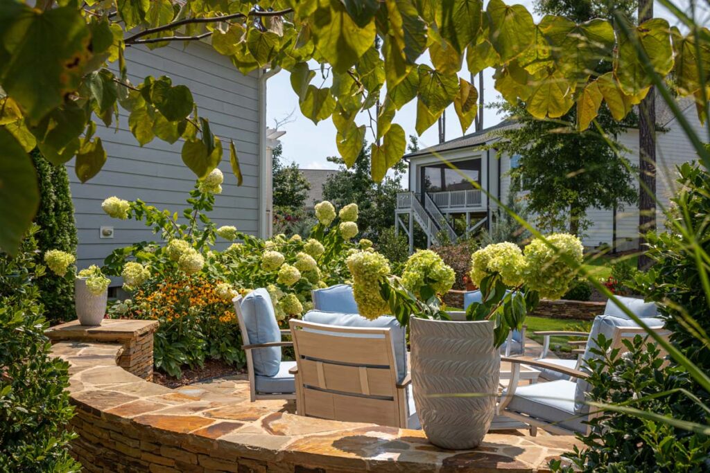 Close up of Silver Dew with trees in the foreground, showcasing patio with blue patio chairs.