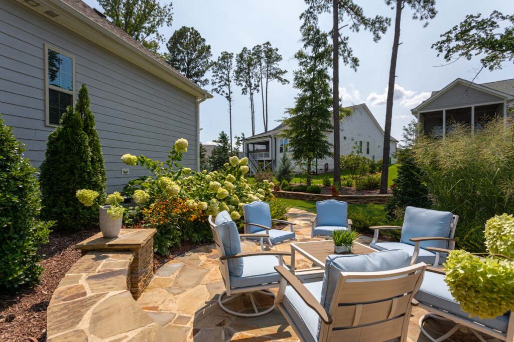 Close up of Silver Dew showcasing patio with blue patio chairs and retaining wall.