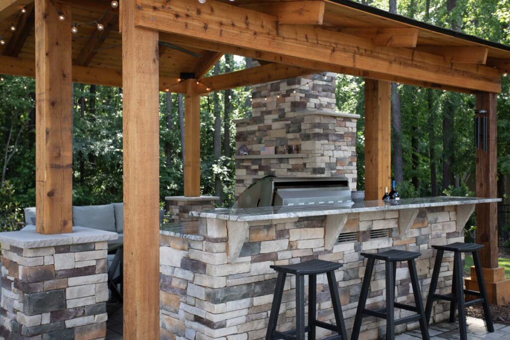 Close up of Swann Trail project showing custom built pavilion, with built-in, fireplace, outdoor kitchen and grill. Focusing on the counter top with three stools.