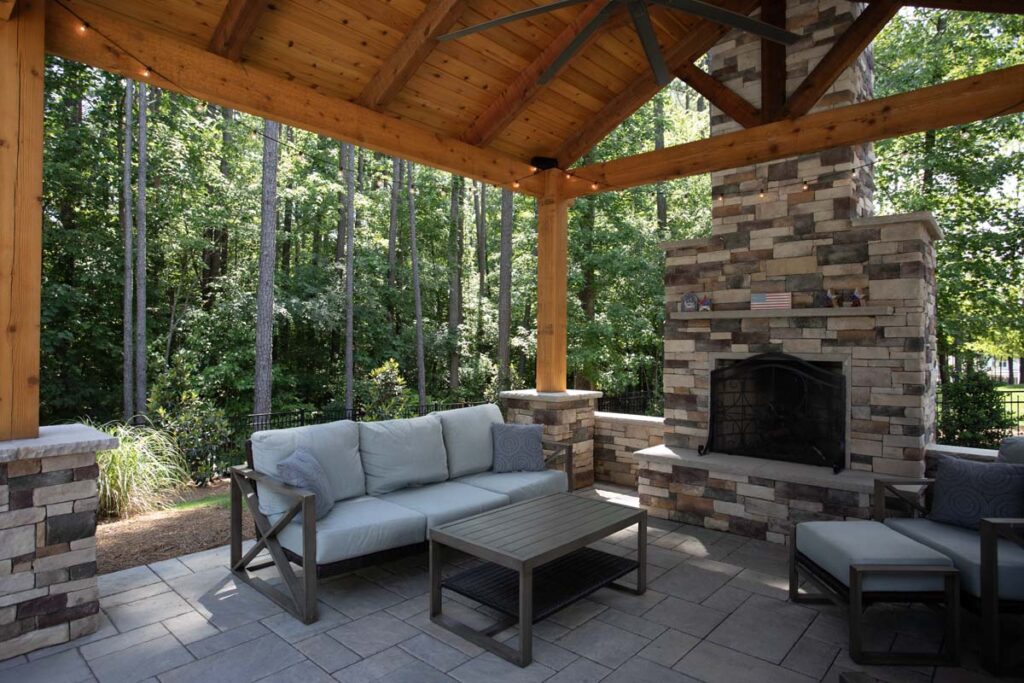 Interior shot of Swann Trail pavilion, showing fireplace, coffee table, outdoor couch, and chair.