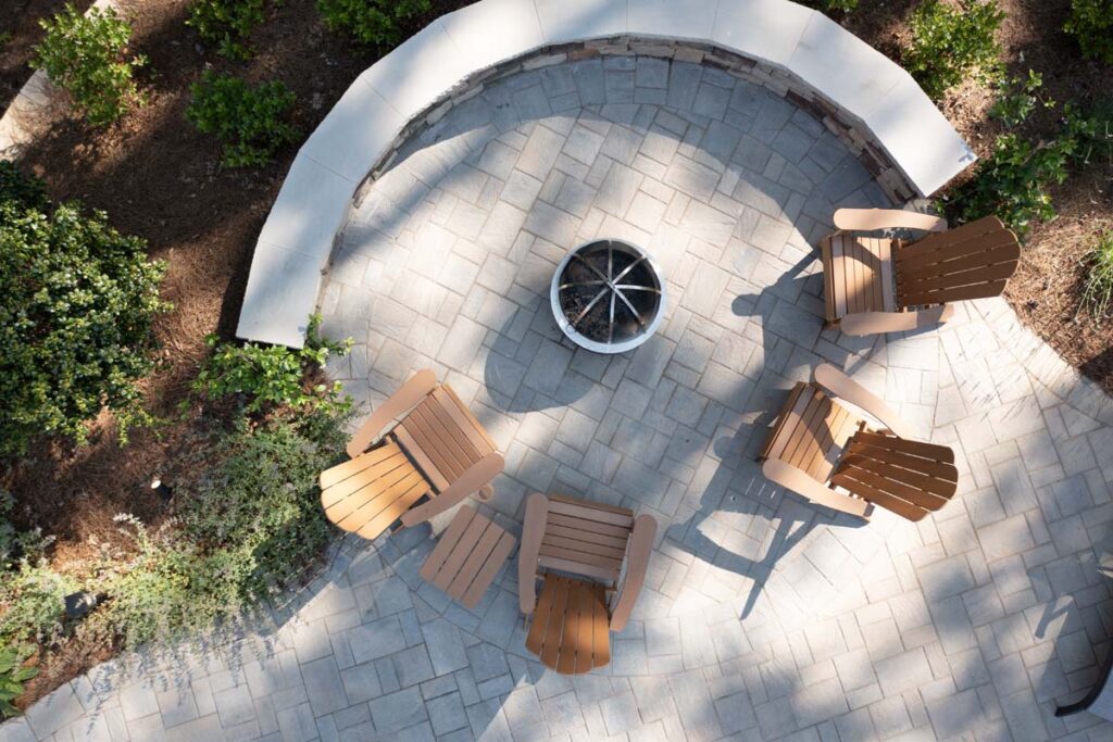 Top view of Swann Trail fire pit with a retaining wall on one half and patio chairs on the other.