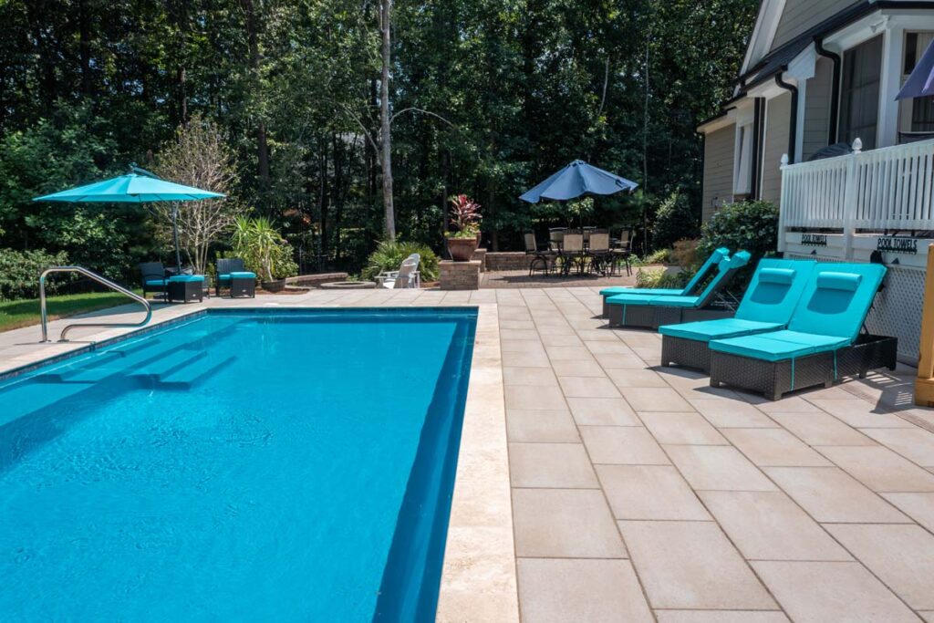 Vision custom pool with Techo-Bloc patio pavers, with fire pit and patio in the background.