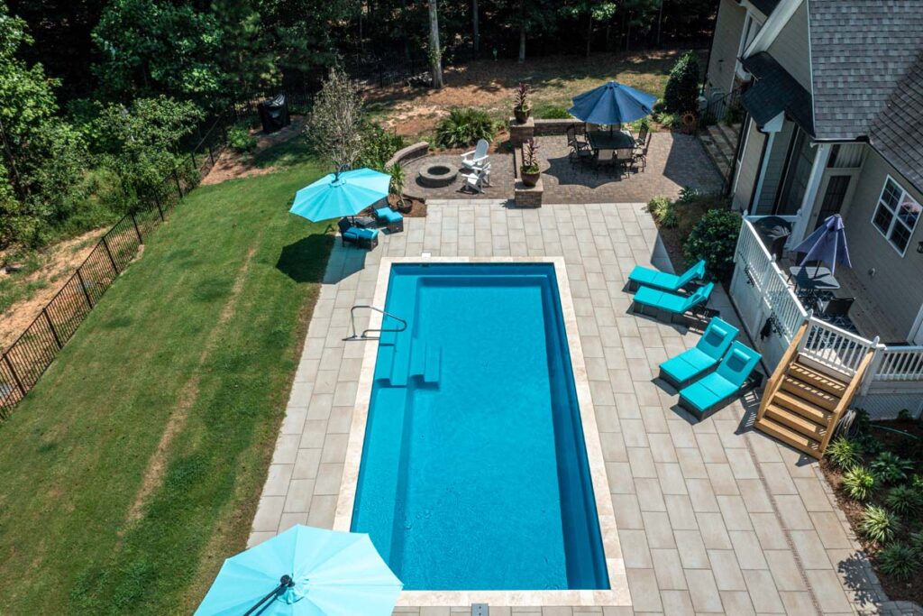 Aerial view of Vision, showing Techo-Bloc patio pavers surrounding pool area, Patio area with fire pit, and deck.