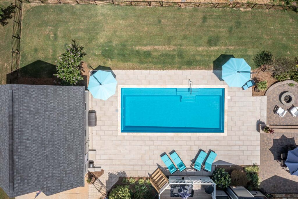 Aerial view of Vision, showing Techo-Bloc patio pavers surrounding pool area. Featuring more of the home and patio area with fire pit.