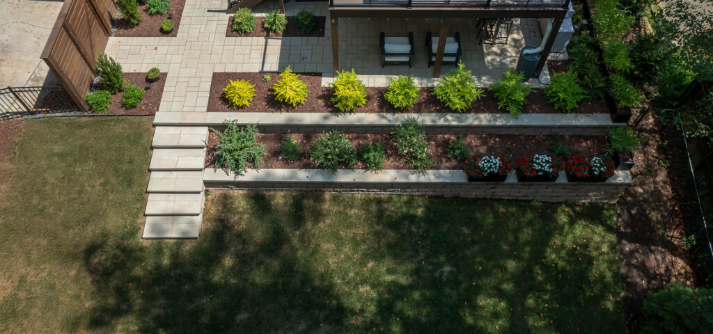 Drone view looking down on Rushing Brook project featuring walkways and patio using Techo-Bloc Blu 60 Pavers in beige and cream. In addition using Belgard Diamond pro for the retaining wall.