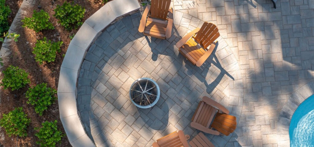 Top view of Swann project with semi-circle retaining wall on the left fire pit with patio chairs in the center, and unique shaped pool on the bottom right corner.